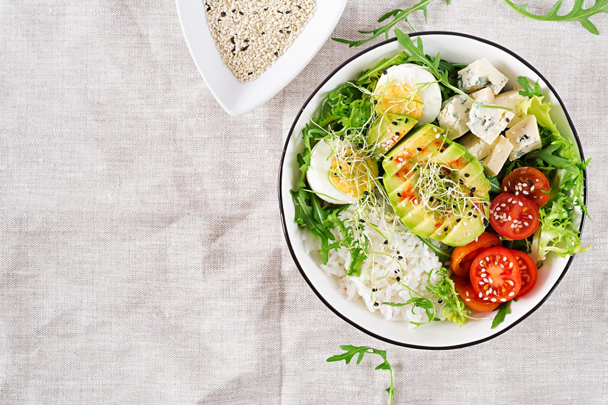healthy green vegetarian buddha bowl lunch with eggs rice tomato avocado blue cheese table 16751600203x2 2SQXsl