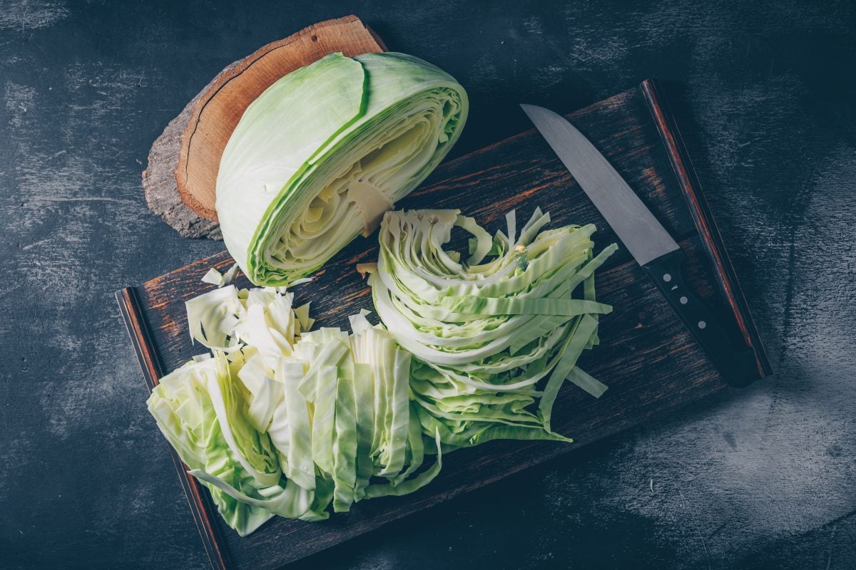flat lay sliced chopped cabbage cutting board knife with wood stub dark textured background horizontal 16772173883x2 CivakC