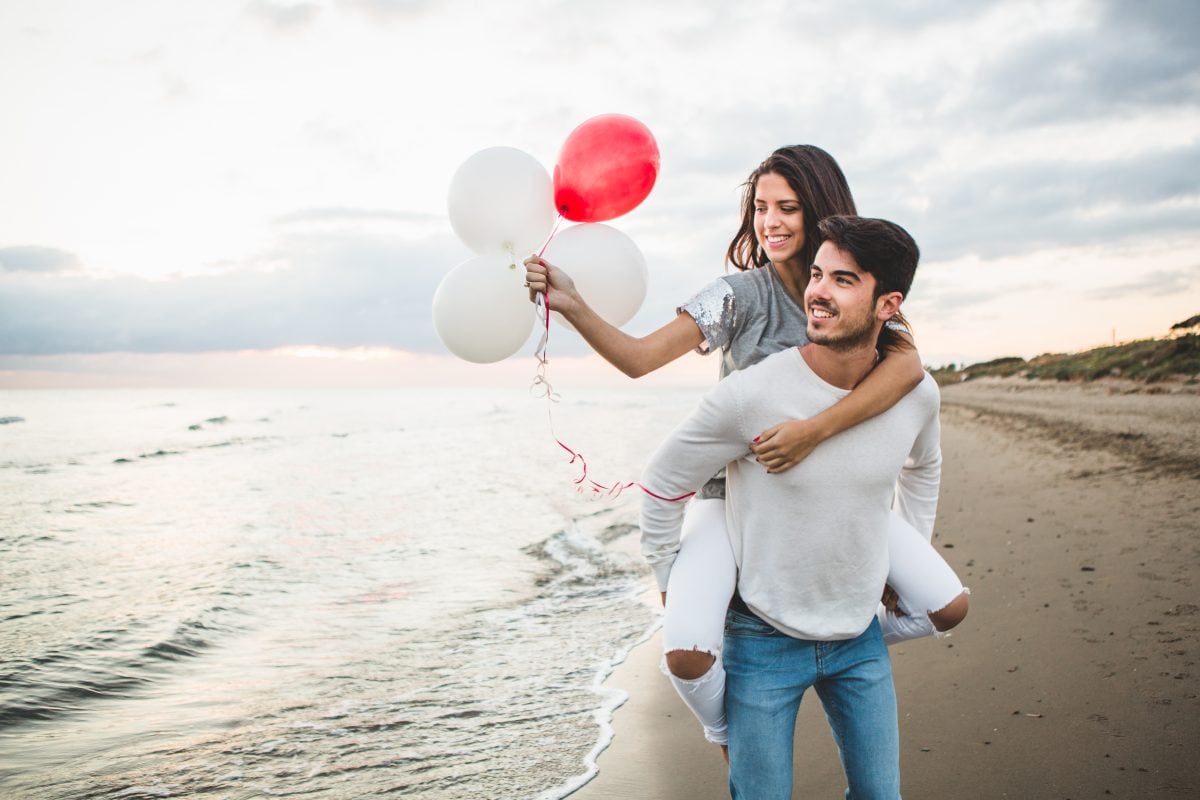girl with balloons while her boyfriend carries her her back 16778133313x2 PY84LV